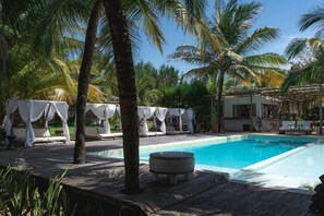 A poolside area with lounge chairs and a covered seating area, surrounded by palm trees. - Zebra Boutique Hotel (Beberibe)