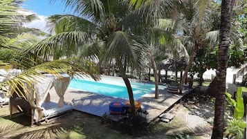 A pool area with palm trees, lounge chairs, and a small inflatable pool.