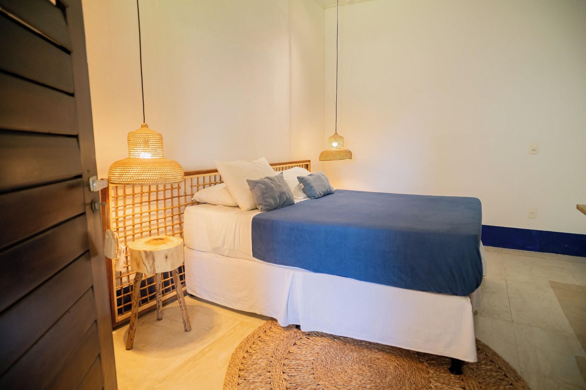 A bedroom with a bed, two bedside lamps, and a small wooden stool.