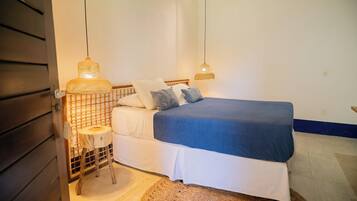 A bedroom with a bed, two bedside lamps, and a small wooden stool.