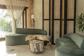 Een moderne woonkamer met een groene bank, een houten salontafel en een vloerlamp.