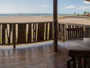Eine Holzterrasse mit Blick auf einen Sandstrand und den Ozean.