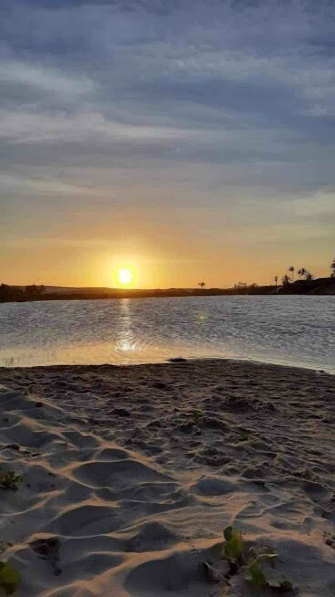 A beach with a sunset over the water.