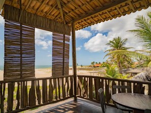 Een houten terras met uitzicht op het strand en palmbomen.