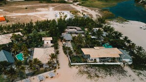 An aerial view of a coastal resort with multiple bungalow-style buildings, a swimming pool, and a beach area. - Zebra Boutique Hotel (Beberibe)