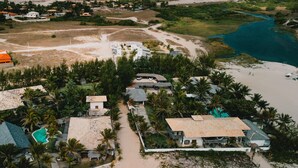 Vista aérea de um resort costeiro com vários edifícios no estilo de bangalô, uma piscina e uma área de praia.