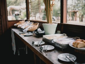 A breakfast buffet setup with various food items and utensils on a wooden table. - Zebra Boutique Hotel (Beberibe)