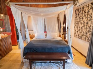 A bedroom with a canopy bed, a wooden bench, a red-framed mirror, and a patterned wall. - Zebra Boutique Hotel (Beberibe)