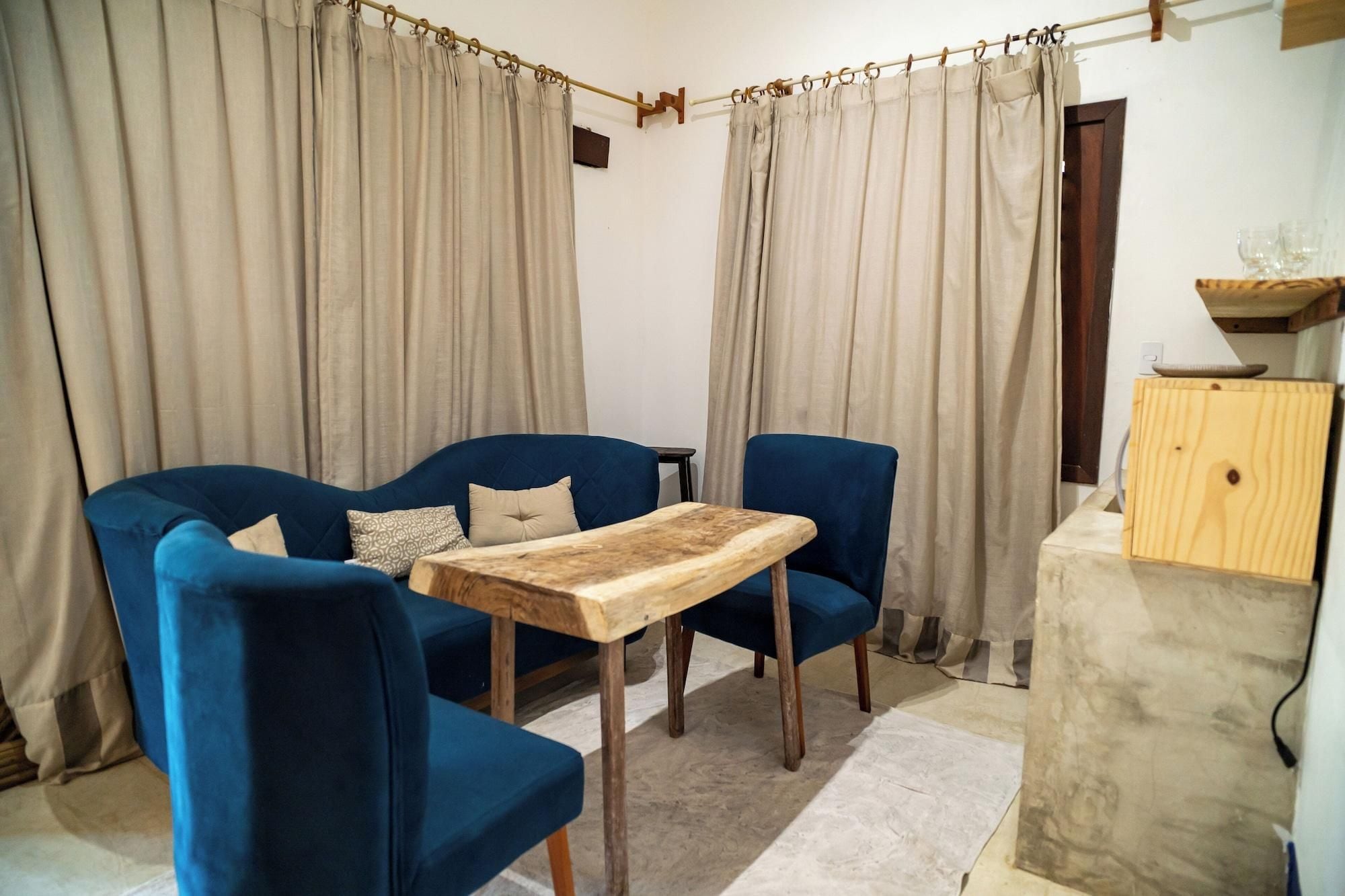 A living room with a blue sofa set, a wooden coffee table, and beige curtains.