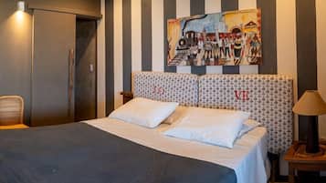 Quarto de hotel com cama, uma cadeira, um quadro na parede e um ar condicionado.