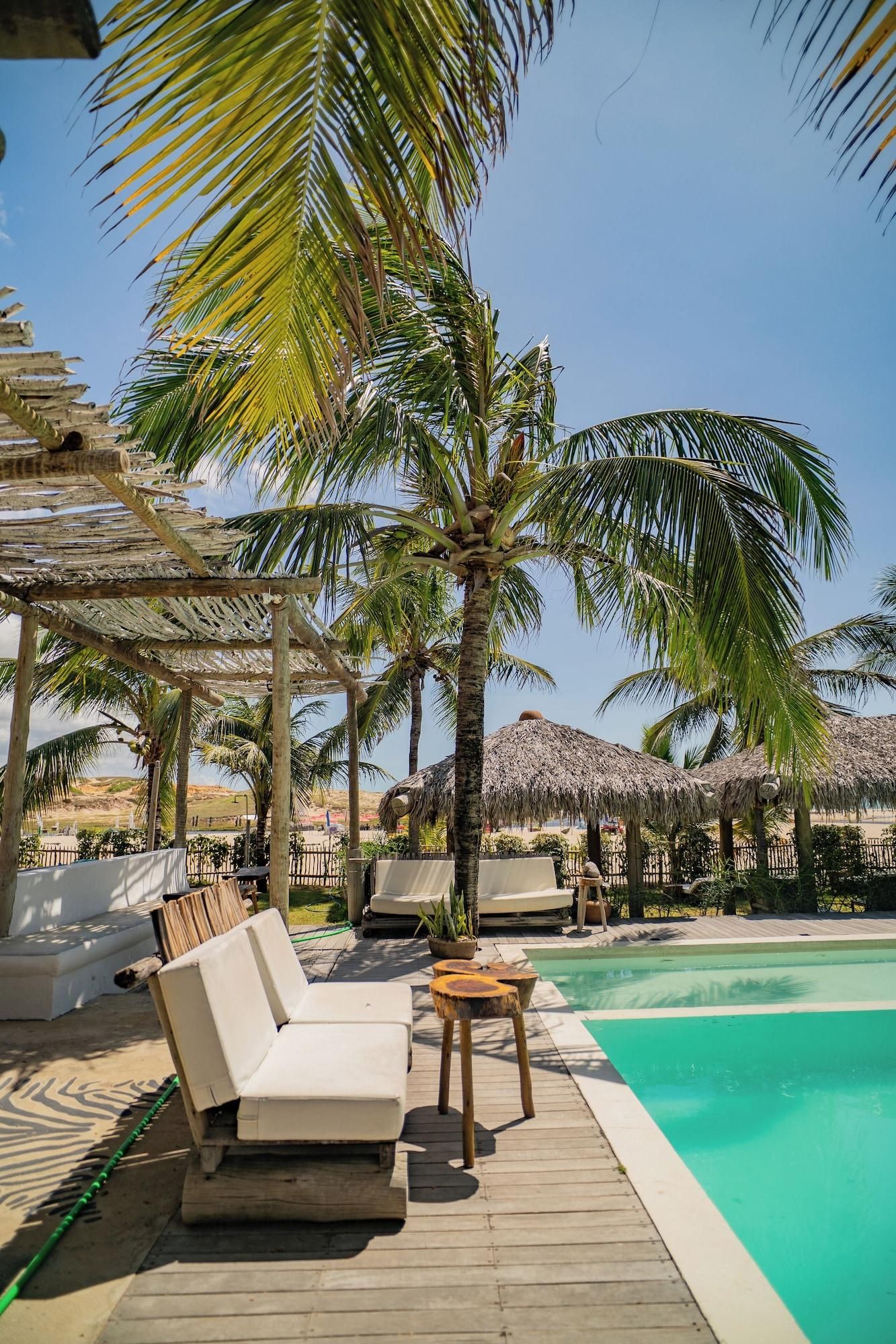 A poolside area with lounge chairs, a wooden deck, and palm trees.
