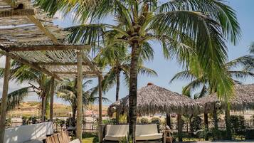 A poolside area with lounge chairs, a wooden deck, and palm trees.