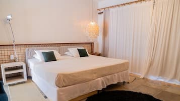 Quarto bem arrumado com cama, mesa de cabeceira, luminária e cortinas.