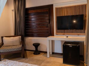 A compact room with a bed, a desk, a television, and a refrigerator. - Zebra Boutique Hotel (Beberibe)
