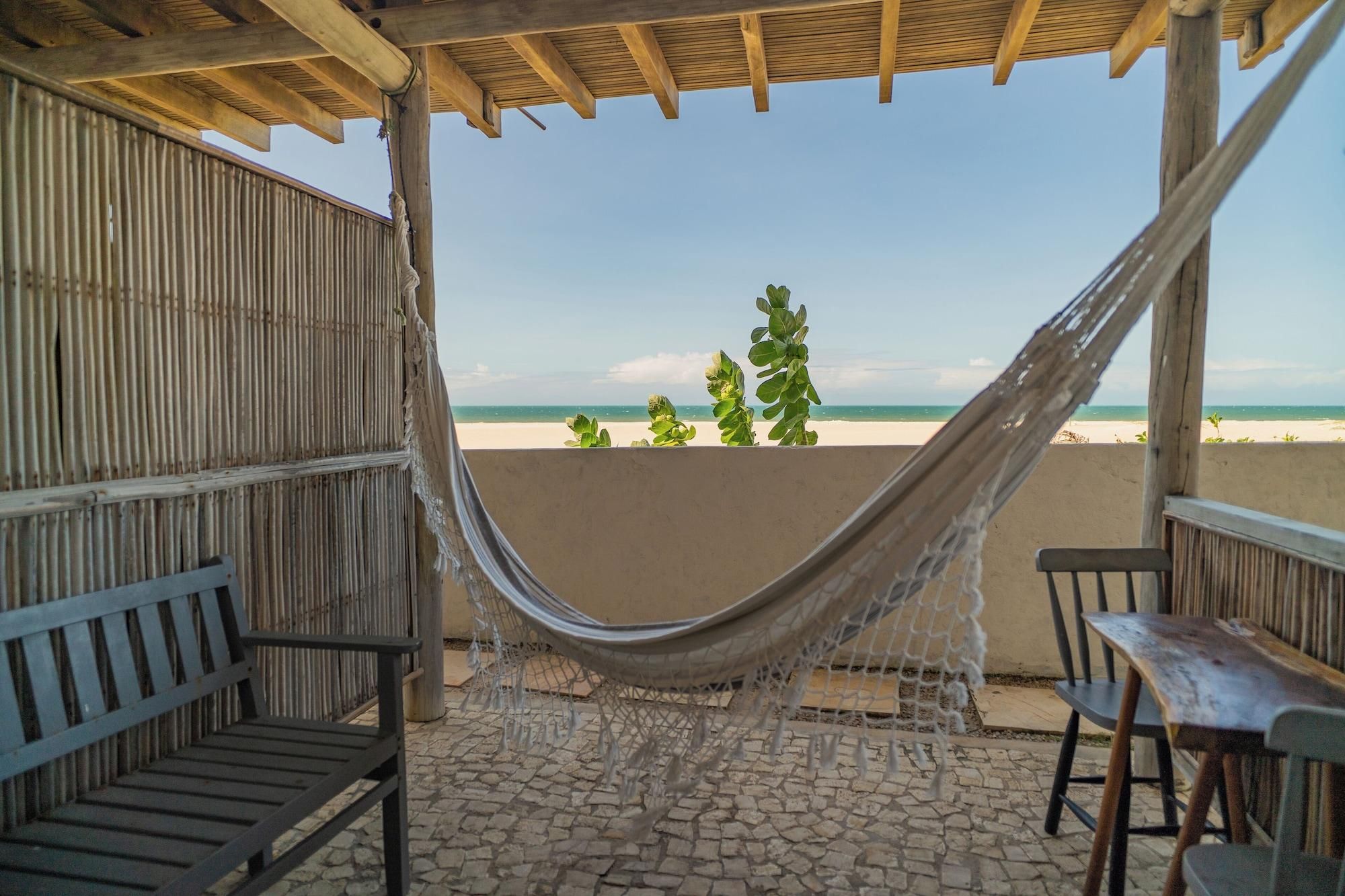 Una hamaca bajo una pérgola de madera con vista a una playa.
