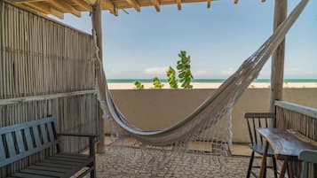 Uma rede sob uma pérgola de madeira com vista para uma praia.