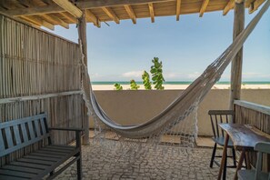 Eine Hängematte unter einer Holzpergola mit Blick auf einen Strand.