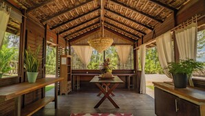 A covered outdoor seating area with a wooden table and benches, surrounded by potted plants and a decorative rug. - Zebra Boutique Hotel (Beberibe)