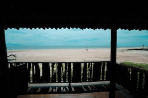 Blick auf den Strand von einer überdachten Sitzgelegenheit mit Holzbalkon.