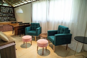 A cozy living area with teal armchairs, a wooden dining table, and a small round table. - Zebra Boutique Hotel (Beberibe)