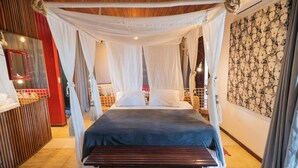 A bedroom with a canopy bed, a wooden bench, a mirror, and a patterned wall. - Zebra Boutique Hotel (Beberibe)