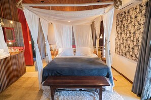 Een slaapkamer met hemelbed, een houten bankje, een spiegel en een kamer met een patroon op de muur.