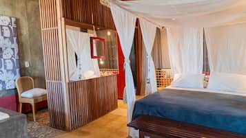 A bedroom with a canopy bed, a bedside table, a chair, and a mirror.