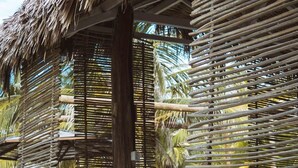 A thatched-roof structure with a wooden bench and cushions, surrounded by woven bamboo walls. - Zebra Boutique Hotel (Beberibe)