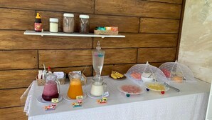 Un bufé de desayuno con diversas opciones de comida y bebidas sobre una mesa, frente a una pared de madera.