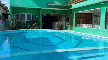 Un edificio verde con piscina, balcón y ventana con vistas.