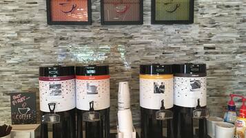 Een koffiehoek met meerdere espresso machines, wegwerpbekers en een dispenser voor Nestle Coffee-Mate.