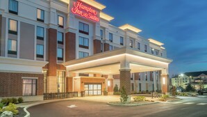 A Hampton Inn & Suites hotel with a modern facade, large windows, and a well-lit entrance.