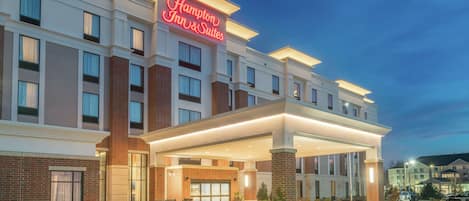 A Hampton Inn & Suites hotel with a modern facade, large windows, and a well-lit entrance.