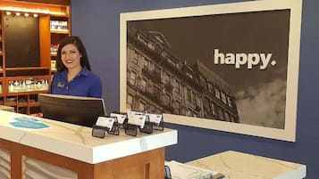 Un mostrador de recepción con un cartel grande en la pared y una persona sentada detrás.