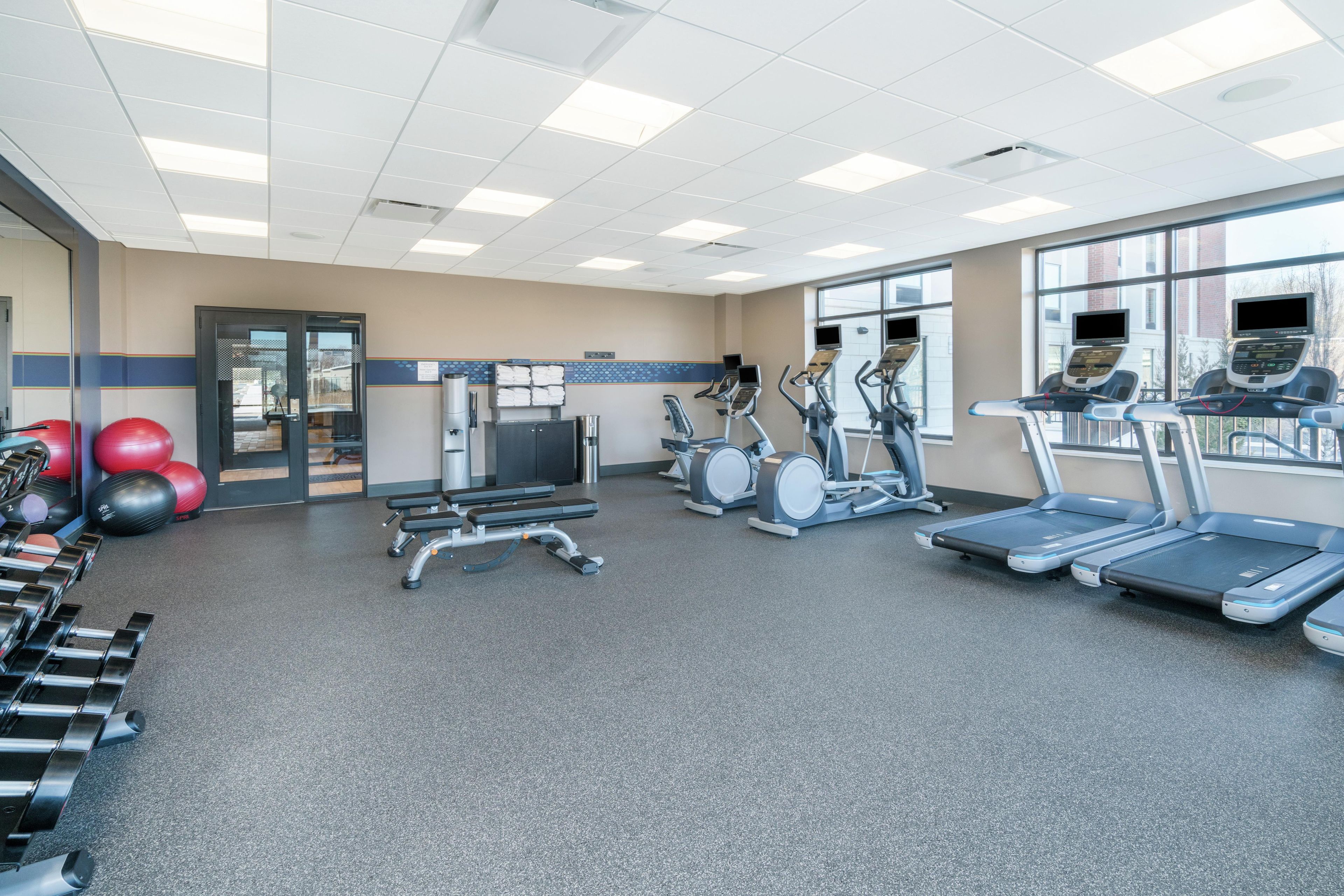 A gym with treadmills, elliptical machines, and free weights.