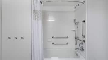 A modern bathroom with a walk-in shower, grab bars, and a white towel hanging on the wall.