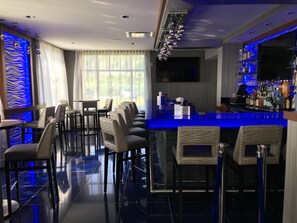 A bar area with a long counter, multiple bar stools, and a variety of bottles. - Hampton Inn & Suites Newburgh Stewart Airport (Newburgh)
