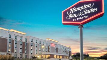Een Hampton Inn & Suites by Hilton hotel met een groot verlicht bord, moderne architectuur en een goed verlichte gevel.