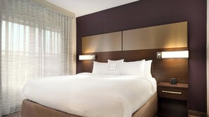 Habitación de hotel con una cama grande, dos mesitas de noche y una ventana con cortinas traslúcidas.