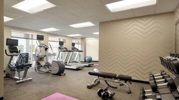 A gym with treadmills, elliptical machines, a bench press, and free weights.