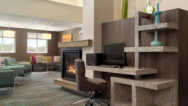 Una sala de estar moderna con chimenea, asientos cómodos, un televisor de pantalla plana y una estantería decorativa.