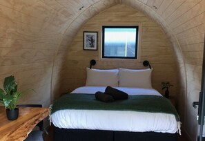 A cozy, arched wooden room with a bed, a small window, and a plant. - Maruia Hot Springs (Lewis Pass)