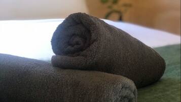 A neatly folded dark-colored towel on a green surface, likely a bed or a towel rack.