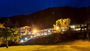 Un edificio moderno con un muro de contención de piedra, amplias ventanas y una entrada bien iluminada.