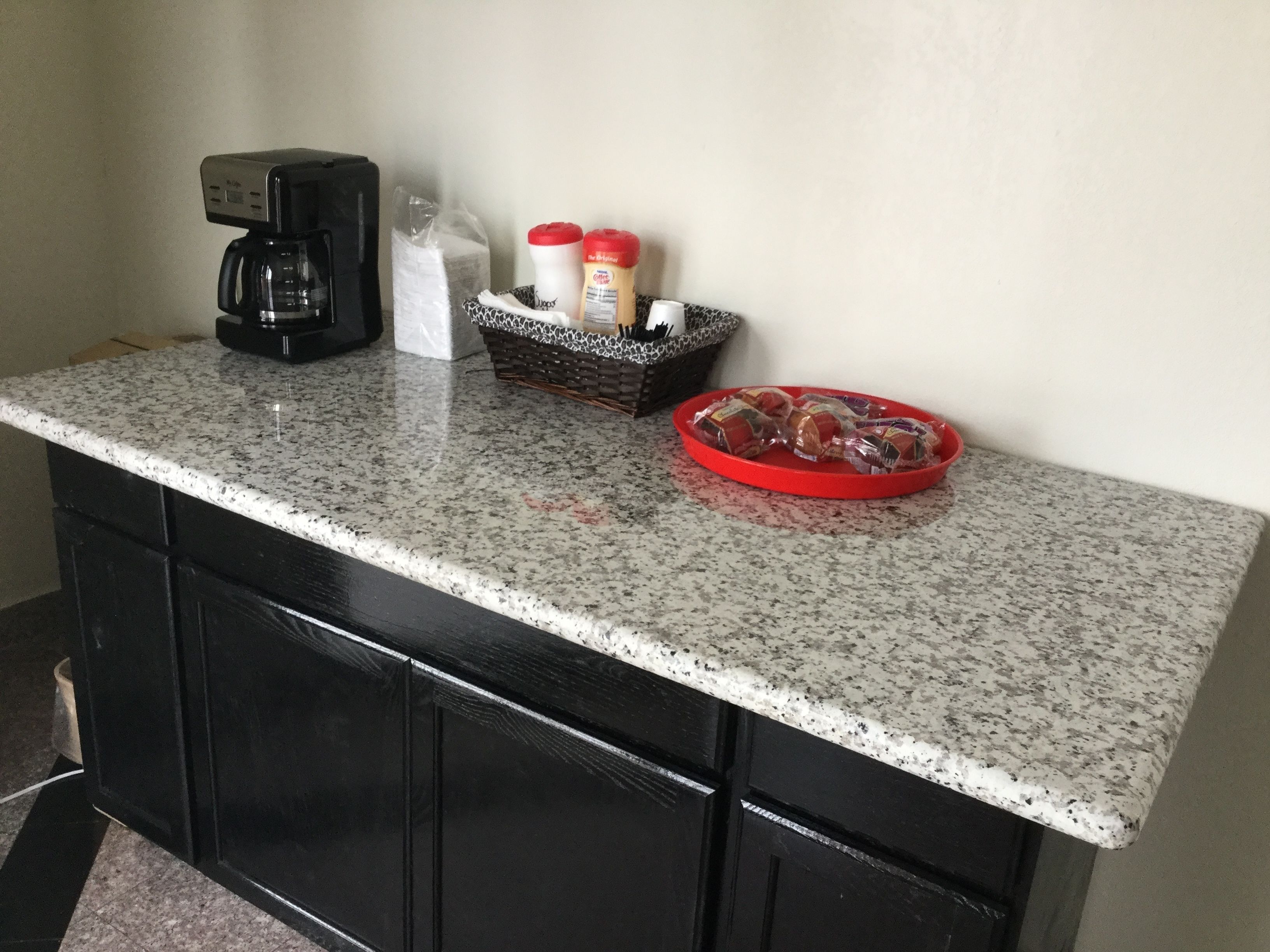 Uma bancada de cozinha com uma cafeteira, uma cesta de pão e acompanhamentos.
