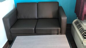 A dark brown sofa against a blue wall, a white radiator, and a grey table. - Moonlight Inn (Houston)