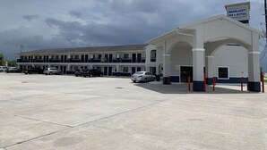 A motel with a large parking lot and a sign for Moonlight Inn & Suites. - Moonlight Inn (Houston)