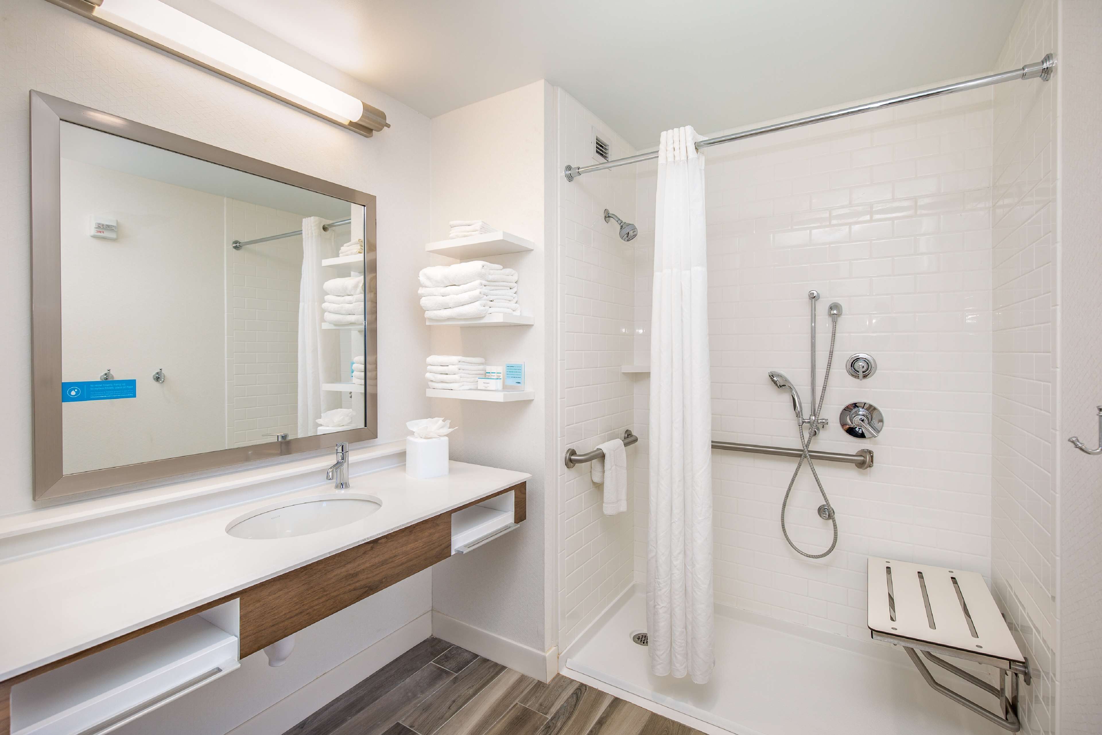 Un baño moderno con lavamanos, espejo y ducha blancos.