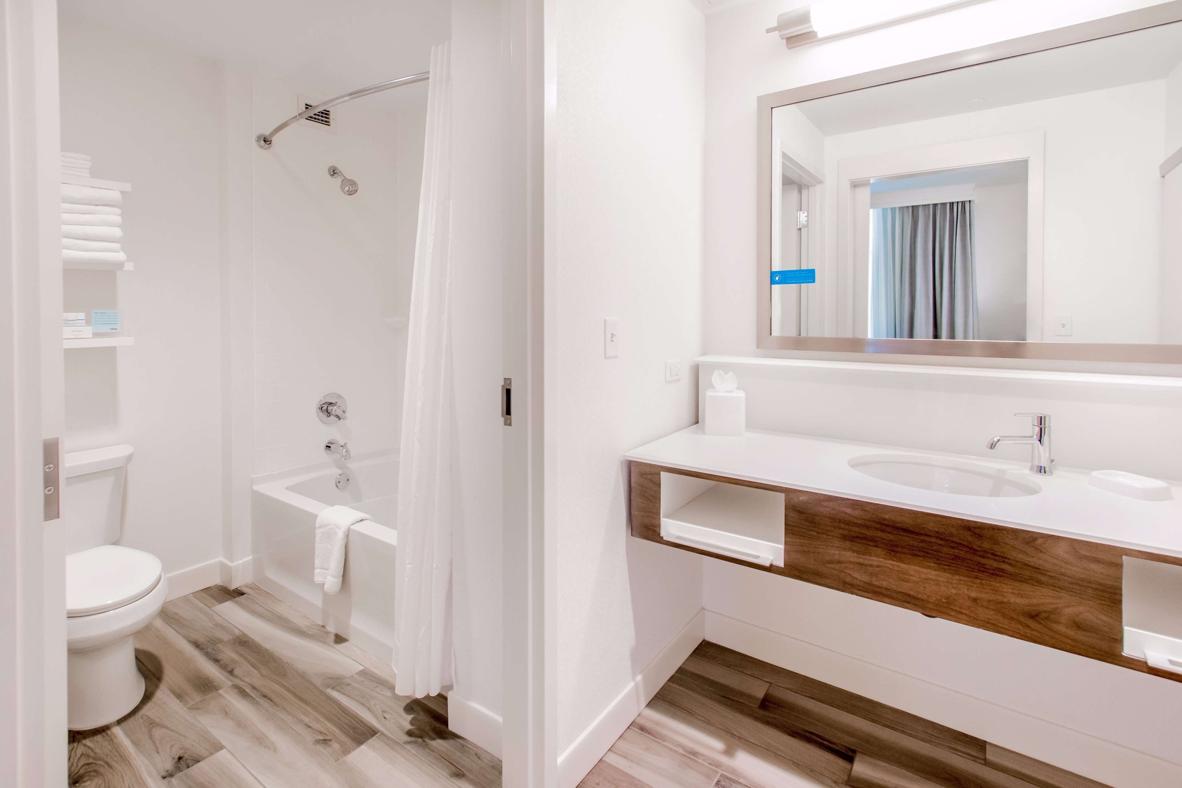 Un baño moderno con inodoro blanco, bañera, ducha y tocador con espejo.