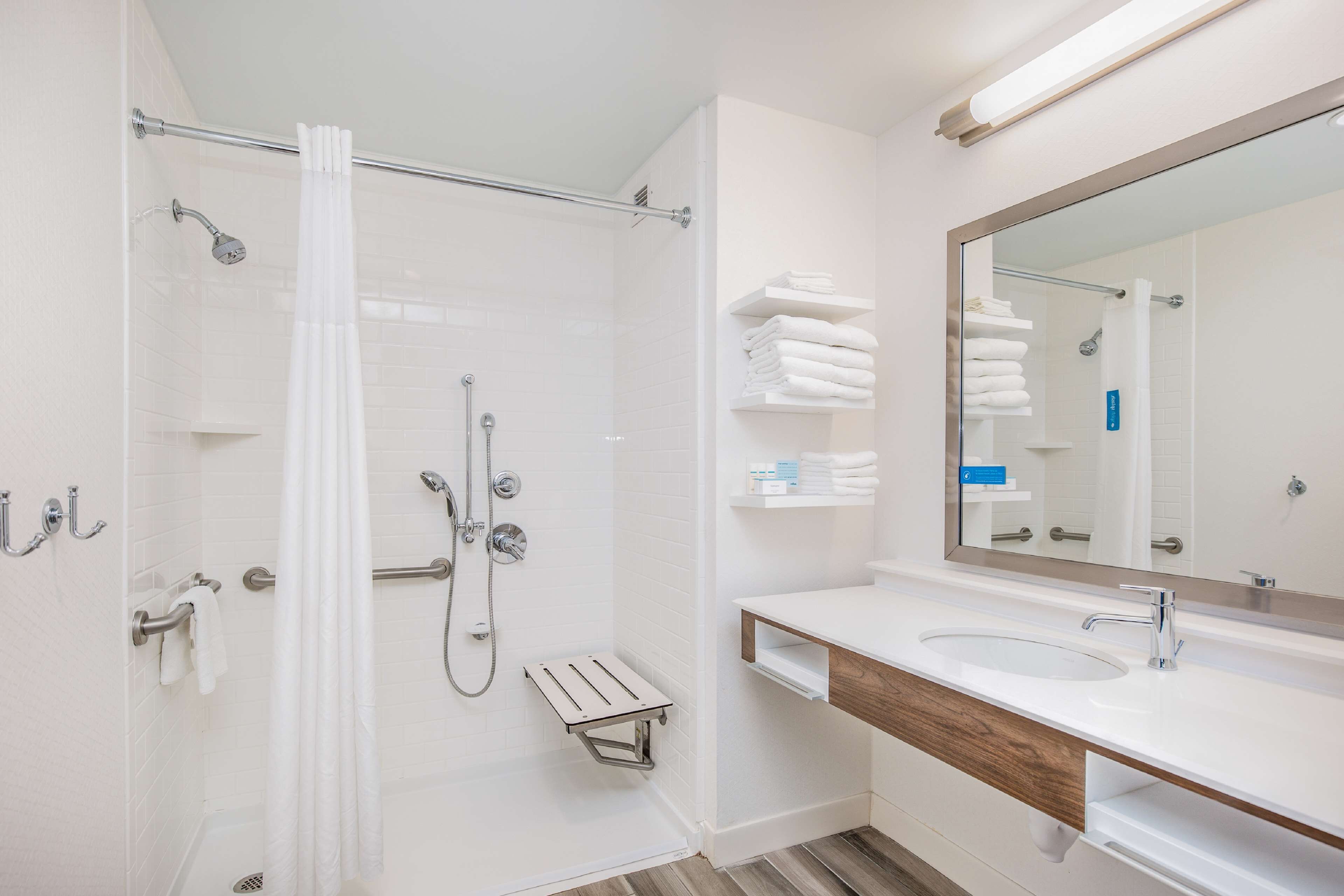 A modern bathroom with a glass shower enclosure, a white sink, and a large mirror.